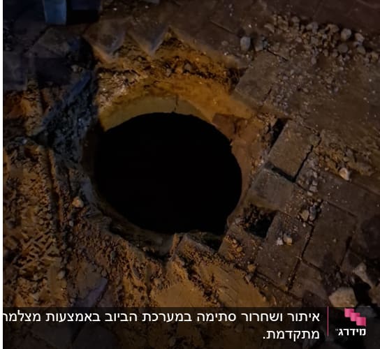 בור פתוח בכביש עם אבנים ועפר סביבו